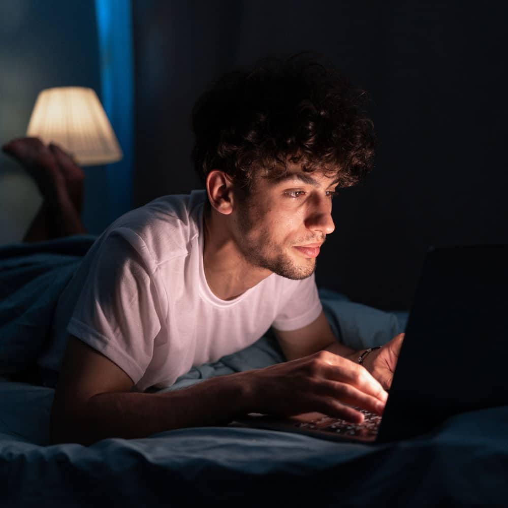 young adult male on laptop at night